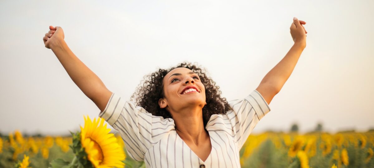 Chica en un campo de girasoles con los brazos estirados