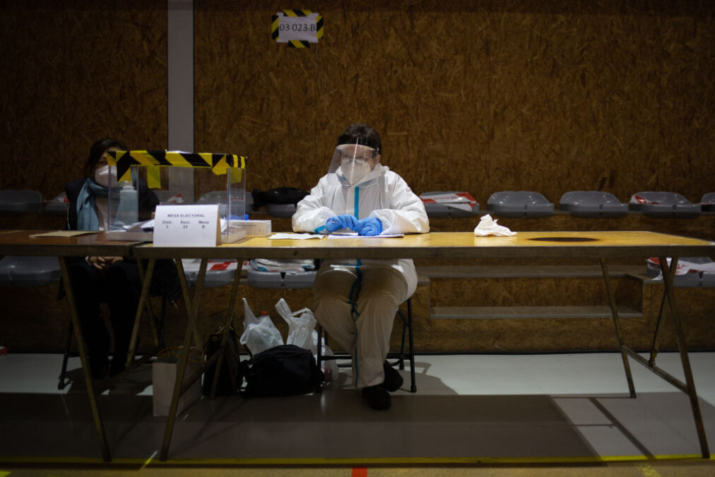 Una mujer con traje EPI en una mesa electoral en Barcelona. Getty.