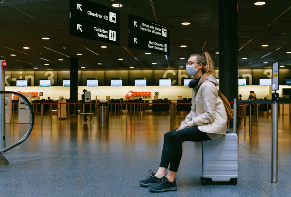 Una chica espera sentada en su maleta dentro del aeropuerto a que salga su avion. Foto: Anna Shvets (Pexels)