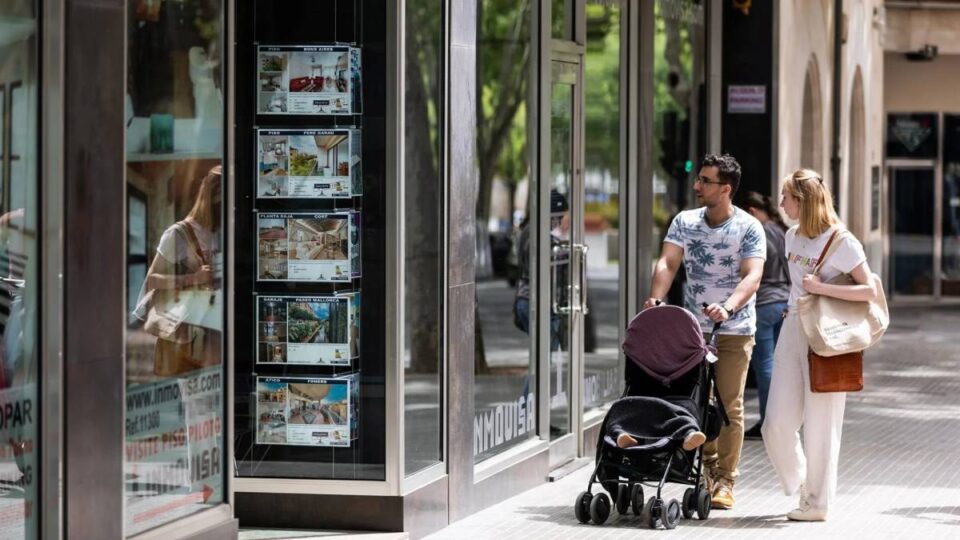 Dos personas observan los anuncios de viviendas en venta en una inmobiliaria en Palma de Mallorca.